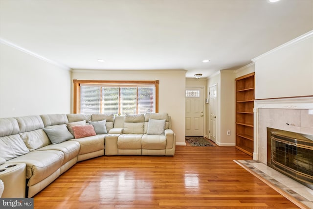 unfurnished living room featuring light wood finished floors, baseboards, ornamental molding, built in shelves, and a fireplace