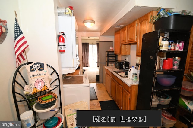 kitchen with light tile patterned flooring, sink, and washer / dryer