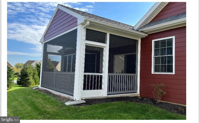 view of side of home featuring a lawn and a sunroom