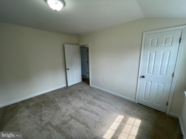 unfurnished bedroom featuring a closet, vaulted ceiling, and carpet floors