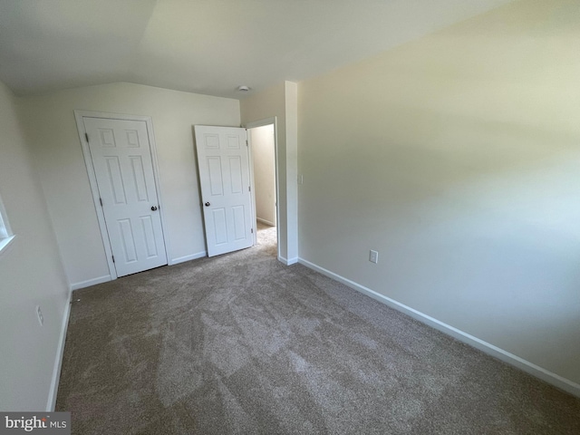 unfurnished bedroom featuring carpet, a closet, and vaulted ceiling