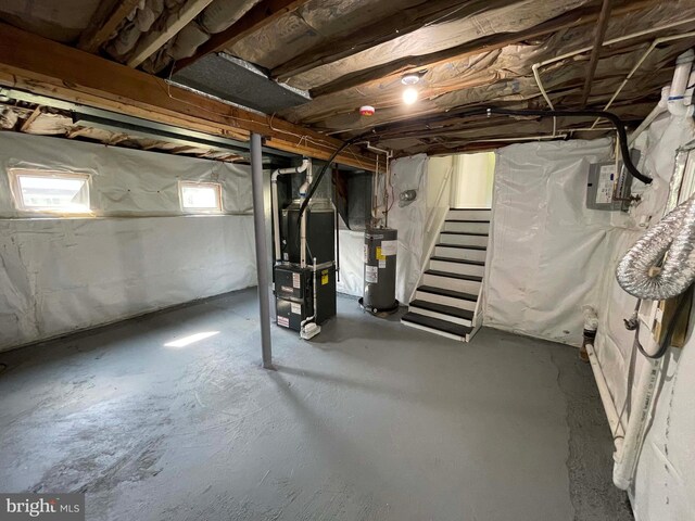 basement featuring electric panel, electric water heater, and heating unit