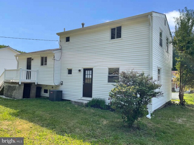 rear view of property featuring a lawn and central AC