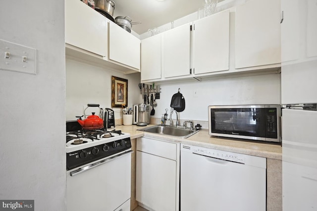 kitchen with light countertops, white appliances, a sink, and white cabinets