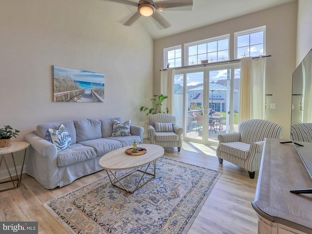 living area with high vaulted ceiling, light wood finished floors, and a ceiling fan