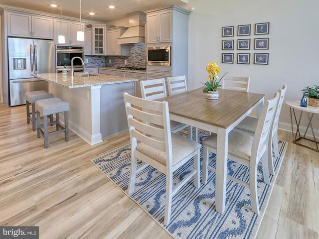 dining room with light wood finished floors, baseboards, and recessed lighting