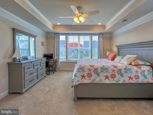 carpeted bedroom with a tray ceiling, ceiling fan, multiple windows, and crown molding