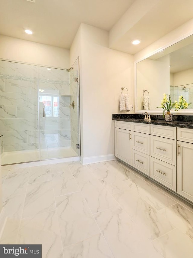 bathroom with marble finish floor, a marble finish shower, vanity, and baseboards