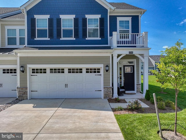 view of front of home featuring a garage, a front lawn, and a balcony