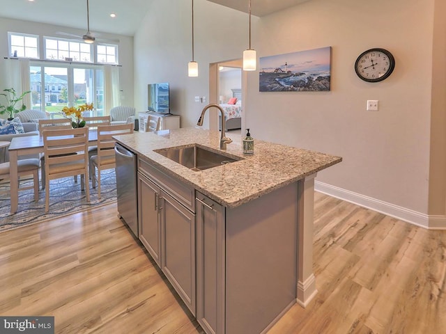 kitchen with ceiling fan, stainless steel dishwasher, an island with sink, light hardwood / wood-style floors, and sink