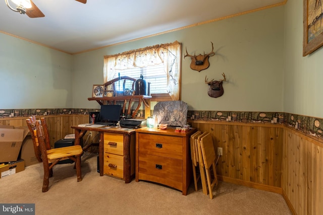 office area with carpet, crown molding, wainscoting, wood walls, and ceiling fan