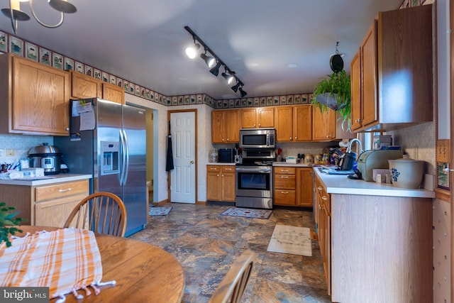 kitchen with backsplash, dark tile patterned floors, stainless steel appliances, sink, and rail lighting