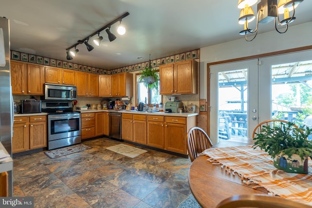 kitchen with dark tile patterned flooring, stainless steel appliances, decorative backsplash, and a notable chandelier