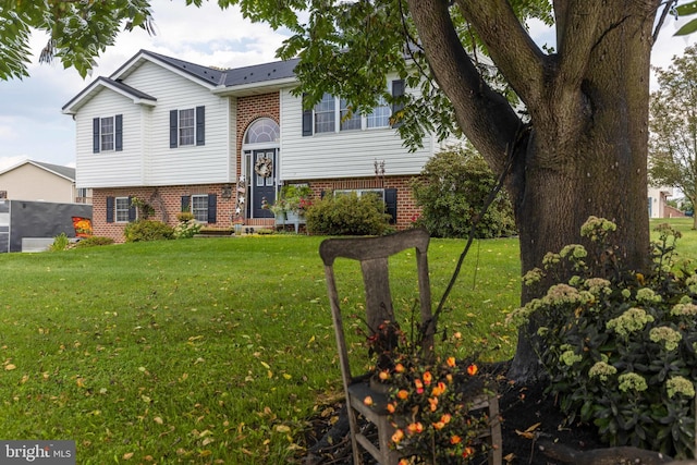 raised ranch with a front lawn and brick siding