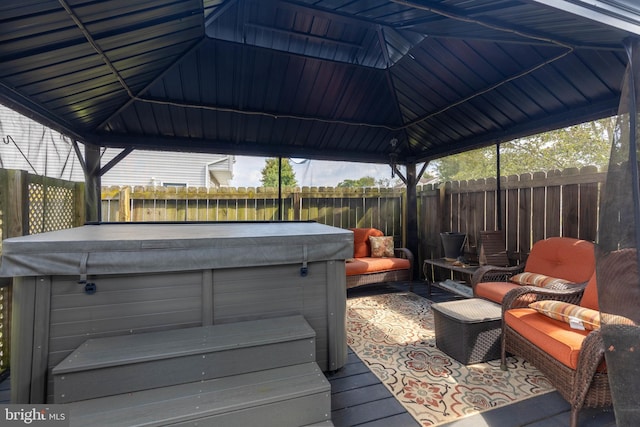 wooden deck featuring a hot tub, fence, and a gazebo