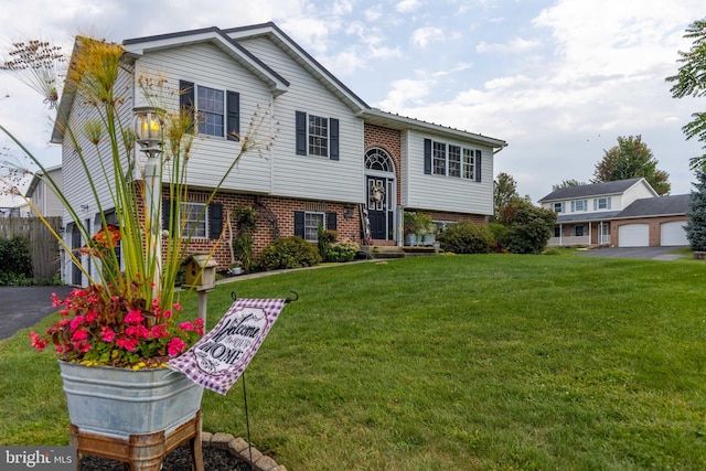 split foyer home with a front yard, fence, and brick siding