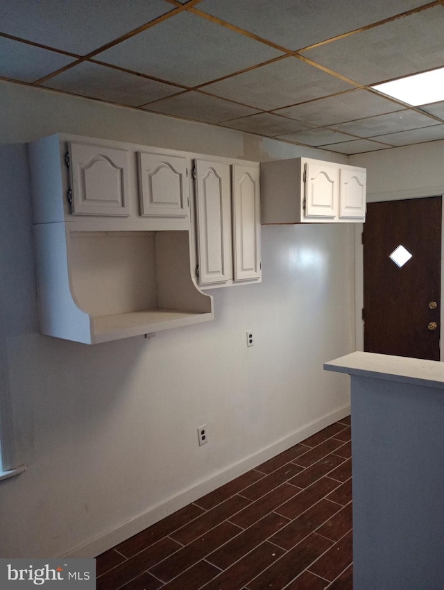 kitchen featuring a drop ceiling and white cabinets