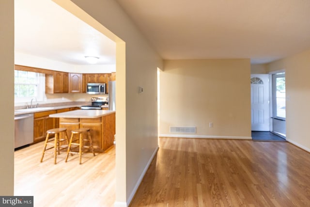 kitchen featuring light wood-type flooring, a center island, sink, a kitchen bar, and stainless steel appliances