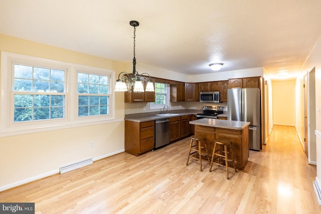 kitchen featuring pendant lighting, sink, a notable chandelier, a kitchen island, and appliances with stainless steel finishes