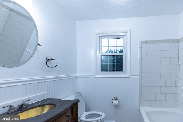 full bathroom with vanity, toilet, a textured ceiling, and separate shower and tub