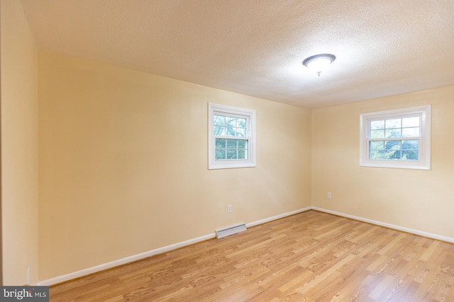 empty room featuring a textured ceiling and light wood-type flooring