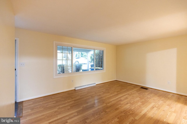 empty room featuring light wood-type flooring and a baseboard heating unit