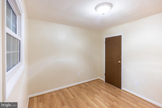 spare room featuring a textured ceiling and light hardwood / wood-style floors