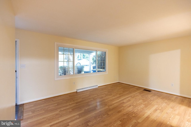 unfurnished room featuring a baseboard radiator and light hardwood / wood-style floors