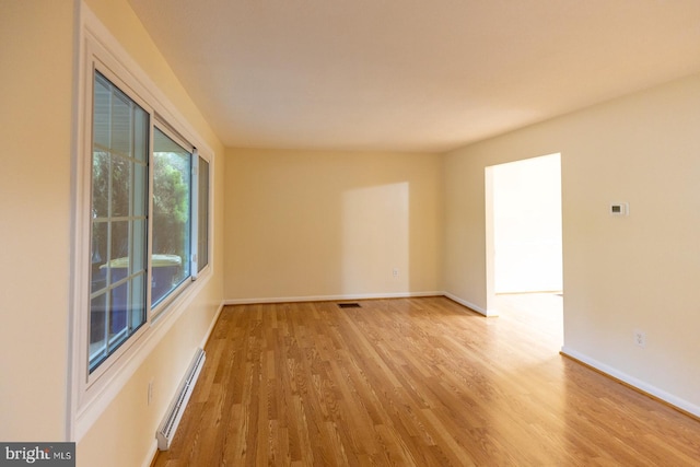 spare room with light wood-type flooring and a baseboard heating unit