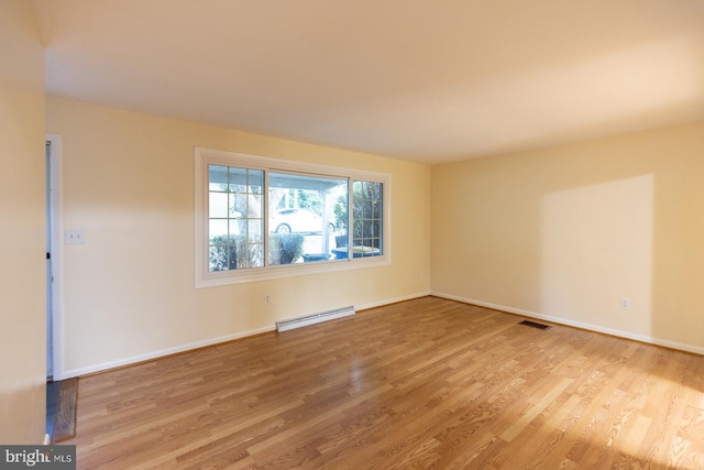 unfurnished room featuring light hardwood / wood-style flooring and a baseboard heating unit