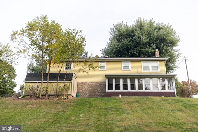 rear view of house featuring a sunroom and a lawn