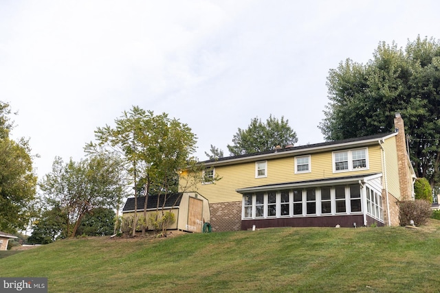 view of front of house with a storage shed, a front lawn, and a sunroom