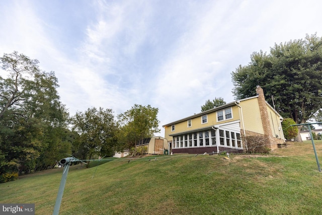 view of front of house with a storage shed, a front lawn, and a sunroom