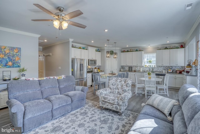 living area with ceiling fan, ornamental molding, light wood-type flooring, and recessed lighting