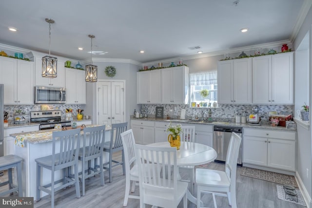 kitchen featuring appliances with stainless steel finishes, a center island, white cabinets, and light hardwood / wood-style flooring