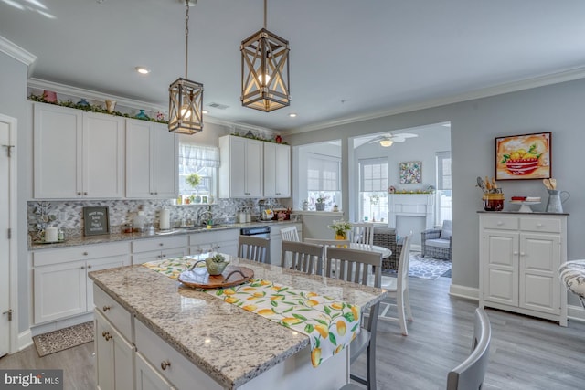 kitchen with white cabinetry, light wood-type flooring, a kitchen island, ceiling fan, and hanging light fixtures