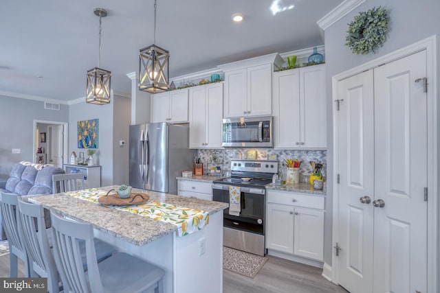 kitchen with backsplash, appliances with stainless steel finishes, light hardwood / wood-style flooring, a kitchen island, and white cabinetry