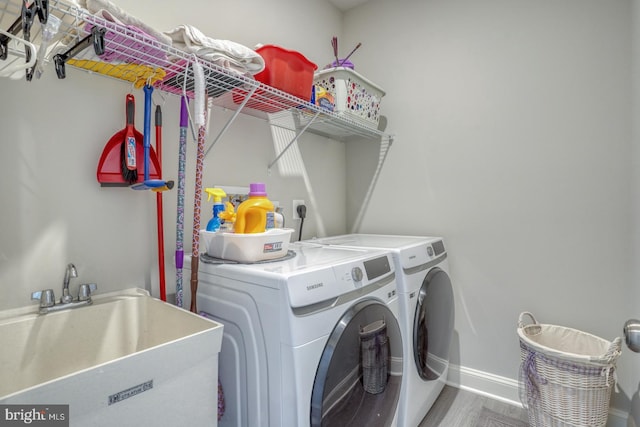 laundry room with separate washer and dryer, sink, and hardwood / wood-style flooring