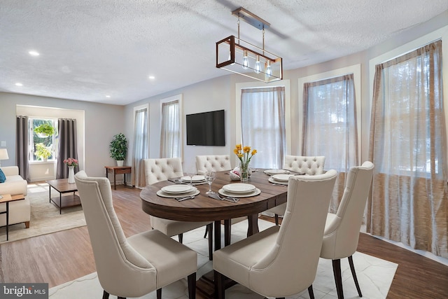 dining room with light wood finished floors, a textured ceiling, and recessed lighting