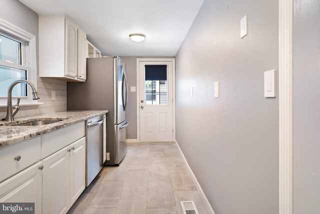 kitchen with visible vents, dishwasher, light stone countertops, white cabinetry, and a sink