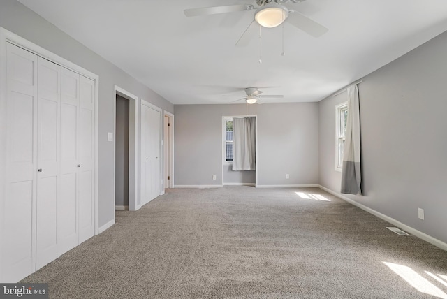 unfurnished bedroom featuring light carpet, a ceiling fan, visible vents, and baseboards