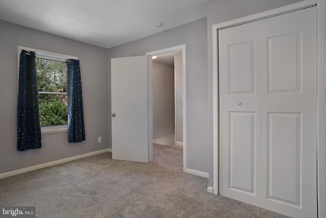 unfurnished bedroom featuring light carpet, baseboards, and a closet