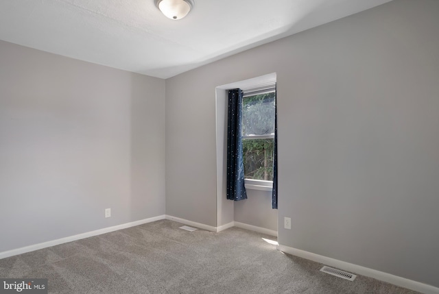 spare room with baseboards, visible vents, and light colored carpet