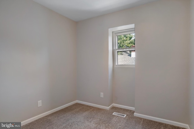 empty room featuring baseboards, visible vents, and light colored carpet