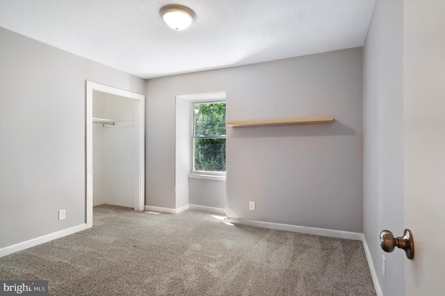 unfurnished bedroom with a textured ceiling, baseboards, a closet, and light colored carpet