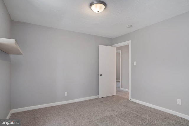 empty room featuring light carpet and baseboards