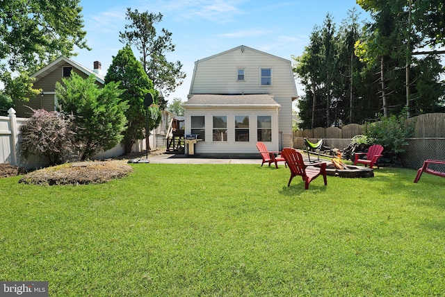 back of property with a fenced backyard, a fire pit, and a lawn