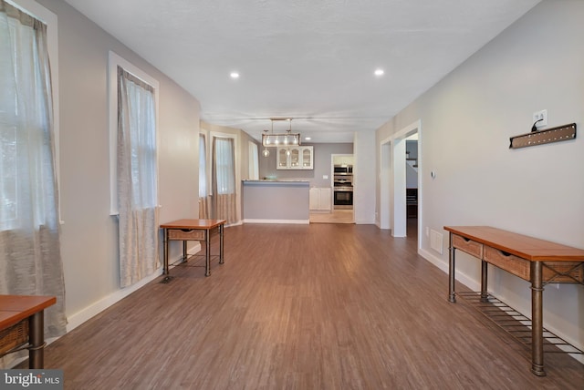 interior space with recessed lighting, a notable chandelier, baseboards, and wood finished floors