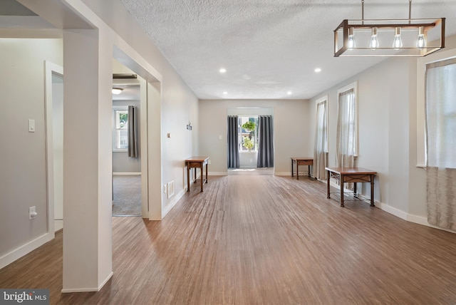 unfurnished room featuring plenty of natural light, a textured ceiling, baseboards, and wood finished floors