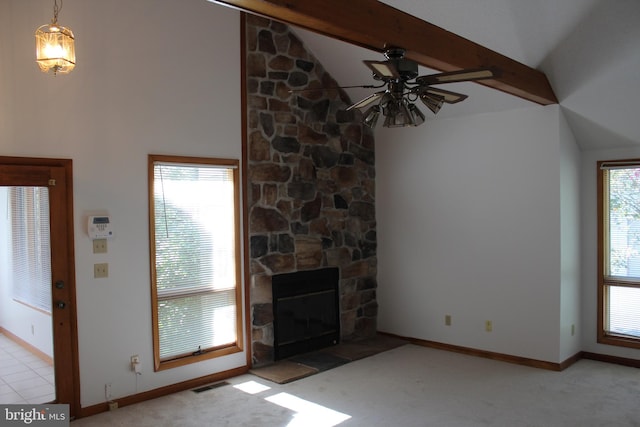 unfurnished living room with ceiling fan, vaulted ceiling with beams, a stone fireplace, and light carpet